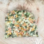 Plastic zak met gemengde diepvriesgroenten op houten ondergrond