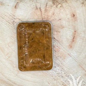 Verpakte gekruide gehaktbal in plastic bakje op houten plank