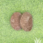 Twee bevroren runderhamburgers op grasachtergrond